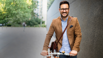 Junger Mann schiebt ein Fahrrad.