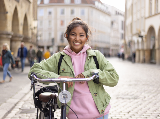 Junges Mädchen steht mit ihrem Fahrrad auf dem Prinzipalmarkt.