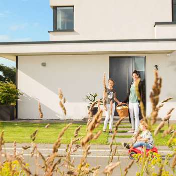 Eine sechsköpfige Familie spielt an einem sonnigen Tag vor Ihrem Haus auf der Straße und Garage